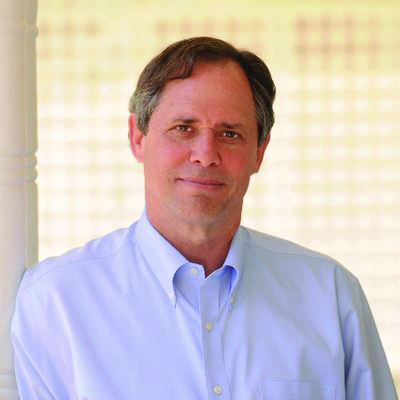 middle aged man in a light button down shirt, no jacket, standing in a bright outdoor setting